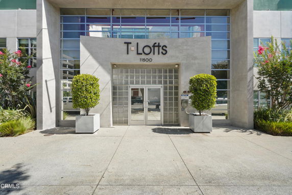 Front view of a modern building with large glass windows and a prominent entrance labeled 'T Lofts'.