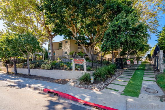 Front view of a residential building with a gated entrance and trees.
