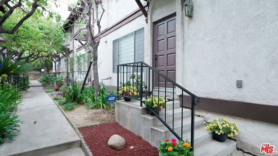 Front view of a building entrance with a staircase and plants.