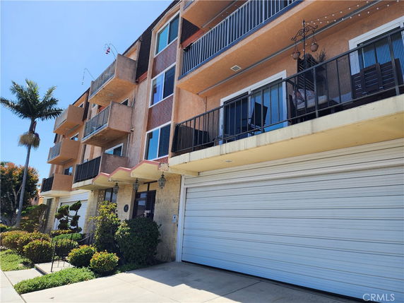 Front view of a multi-story residential building with balconies and a garage.