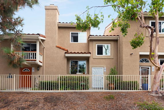 Front view of a two-story house with a fenced entrance and balconies.