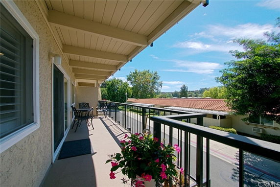Balcony with outdoor seating overlooking building rooftops and trees.