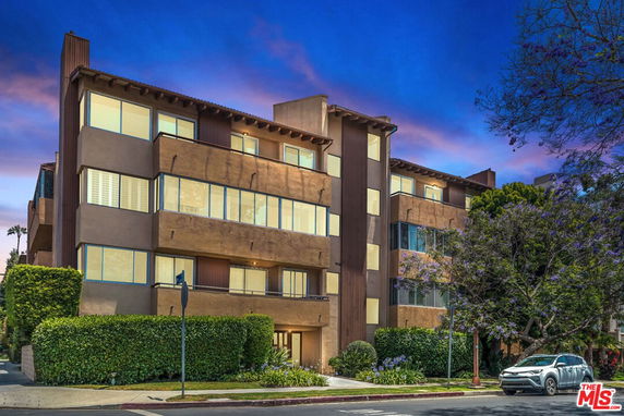 Front view of a multi-story apartment building with large windows.