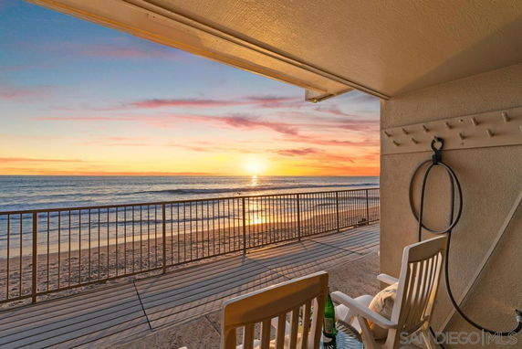 Beachfront view with sunset over the ocean seen from a covered outdoor area.