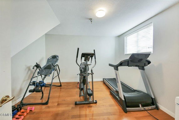 Room with exercise equipment including a treadmill and elliptical machine.