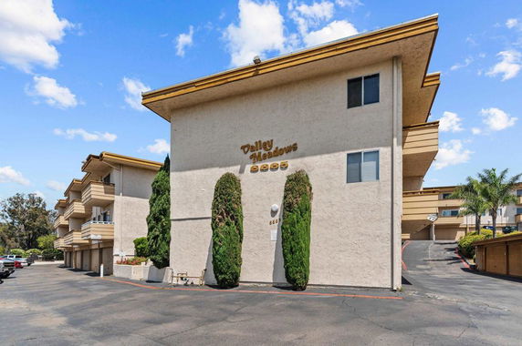 Front view of a multi-story building with balconies and a driveway.