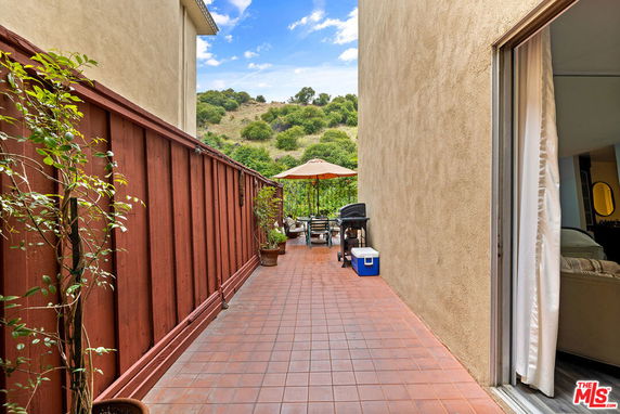 Outdoor patio view with a wooden fence and surrounding greenery.