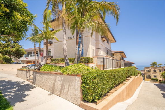 Front view of a multi-story house with balconies and a sloped driveway.