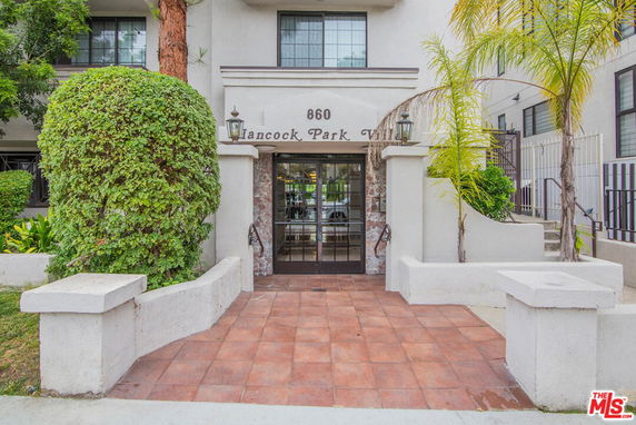Front view of a building entrance with decorative pillars and greenery.