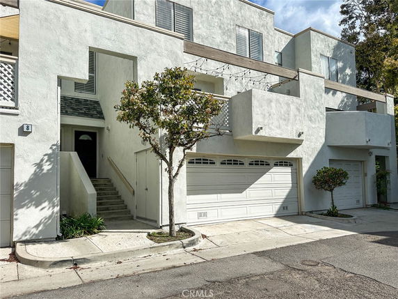 Front view of a multi-story house with garages and balconies.