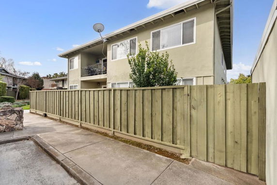 Front view of a two-story residential building with a wooden fence.