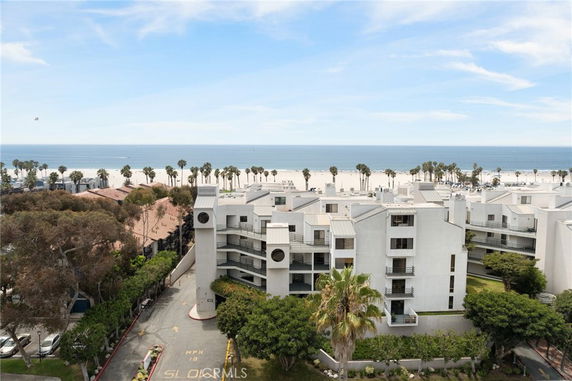 Aerial view of a residential building complex near a beach with a clear ocean backdrop.