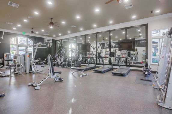 Room with gym equipment including treadmills and weight machines.