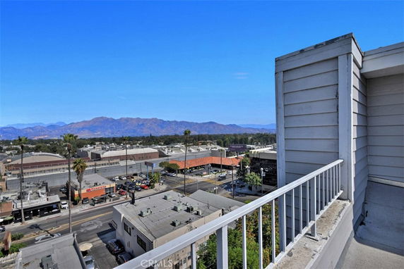 Panoramic view of a cityscape with mountains in the background, seen from a building's balcony.