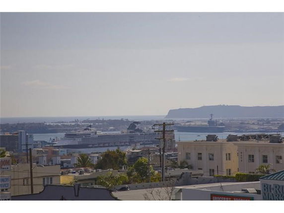 Panoramic view of a cityscape with buildings and water, showing a large ship in the background.