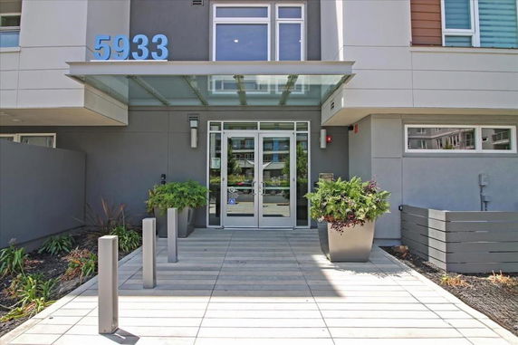 Front view of a building entrance with large glass doors and a planter.