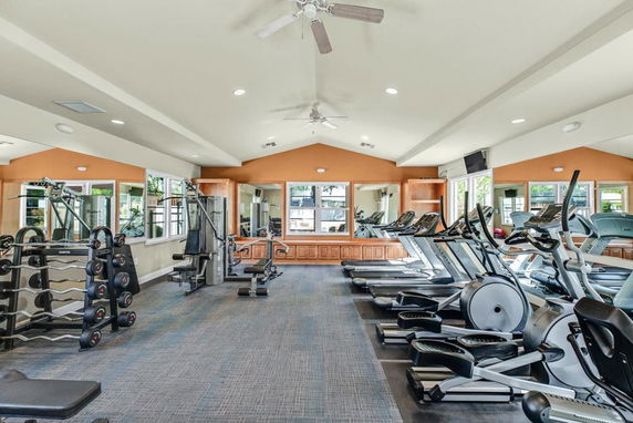 Indoor gym area with exercise machines and free weights.