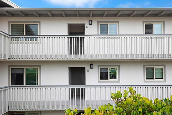 Front view of a multi-story building with balconies and numbered doors.