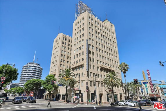 Front view of a tall, multi-story building with architectural details on a busy street corner.