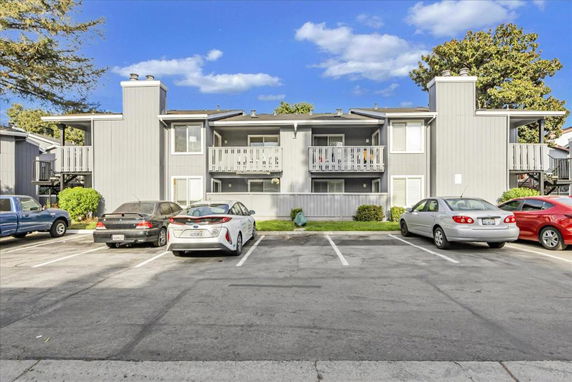 Outdoor parking area in front of a two-story residential building with balconies.
