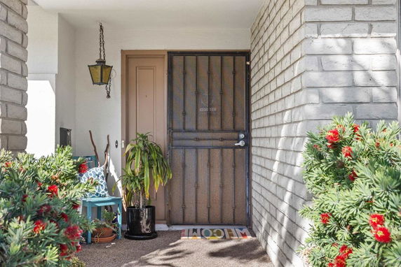 Front view of a house entrance with a metal door and brick walls.