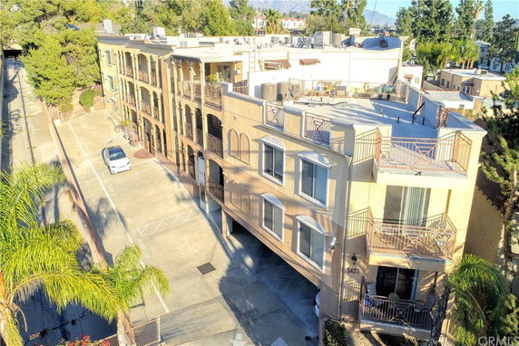Aerial view of a multi-story residential building with balconies and a parking area.