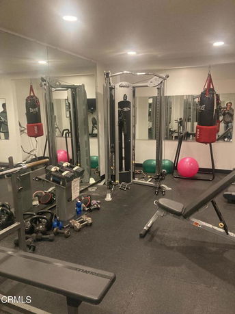Indoor gym area with various exercise equipment and mirrors.