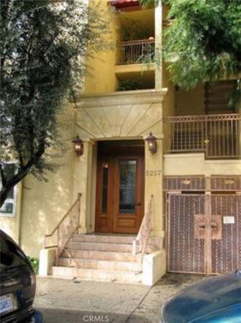 Front view of a building entrance with steps leading up to a wooden door.