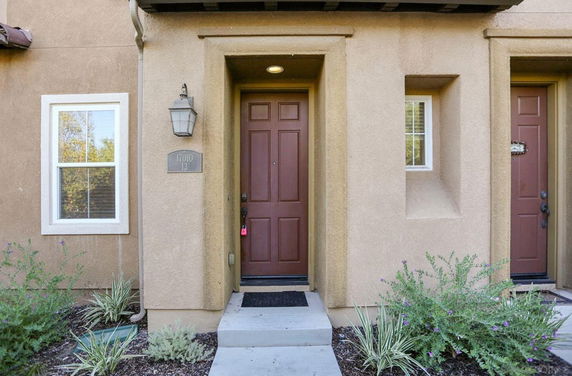 Front view of a house with a brown door and small garden area.
