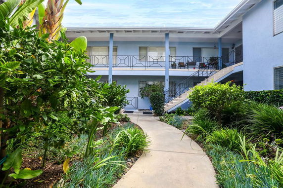 Front view of a two-story building with a walkway and greenery.