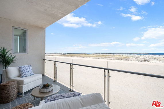 Balcony view overlooking a sandy beach and ocean.