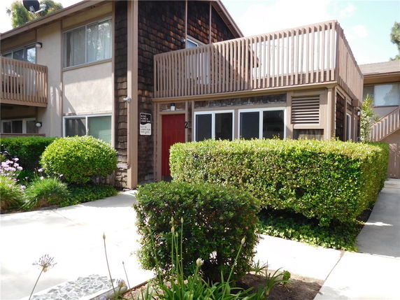 Front view of a two-story residential building with a large balcony on the upper floor.
