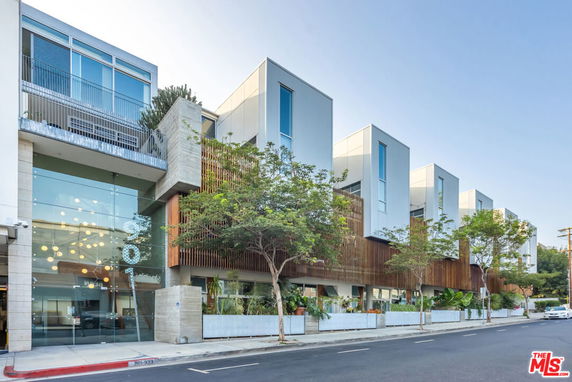 Front view of a modern multi-story building with large glass windows and a wooden facade.
