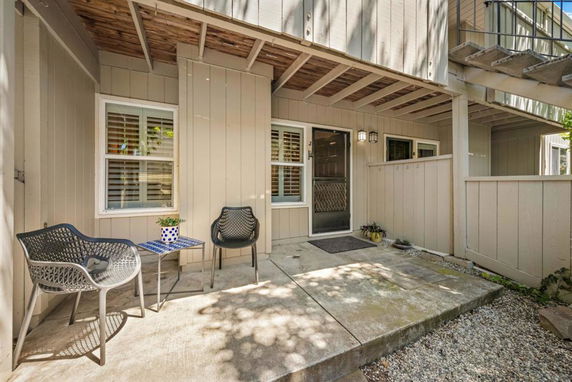 Front view of a building entrance with a small patio area and chairs.