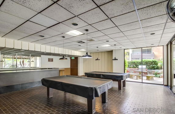 Recreational room with covered pool tables and large windows.
