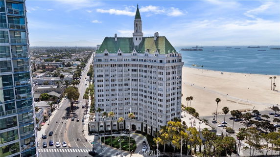 Front view of a multi-story building with a green rooftop near the beach.