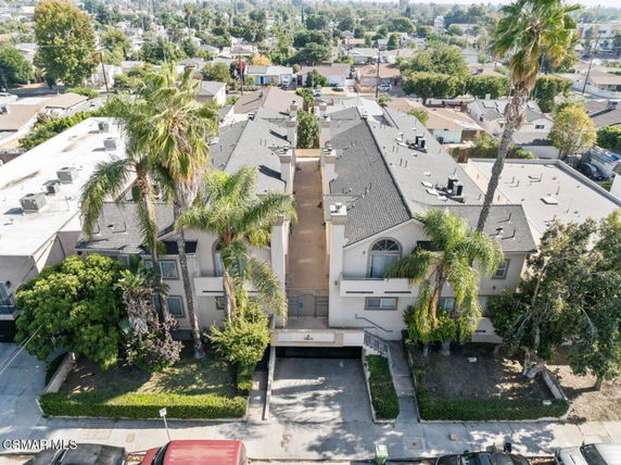 Front view of a multi-story residential building with a central entrance and surrounding palm trees.