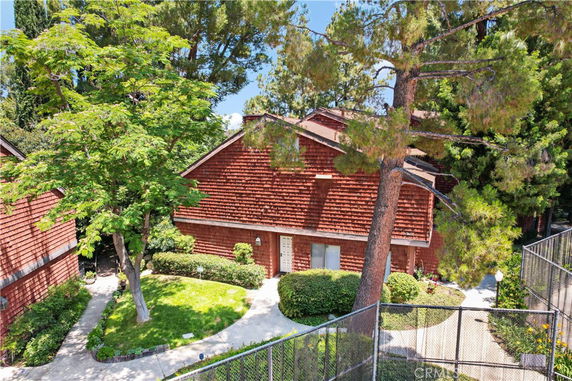 Front view of a two-story house with a wooden exterior and surrounding trees.