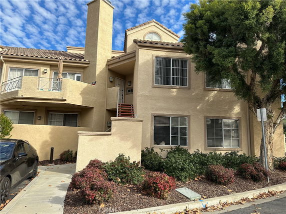 Front view of a two-story house with beige exterior and balcony.