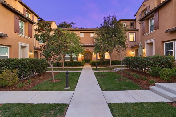 Front view of a two-story residential building with arched entrance and landscaping.