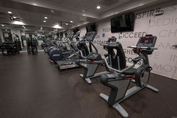 Indoor gym area with exercise machines and motivational wall decor.