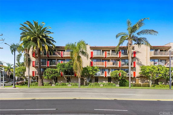 Front view of a multi-story building with balconies and palm trees.