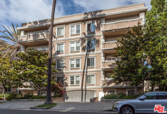 Front view of a multi-story residential building with balconies and beige exterior.