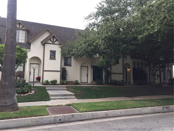 Front view of a two-story house with a gabled roof and arched entrance.