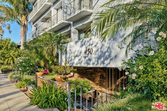 Front view of a multi-story building with balconies and lush landscaping.
