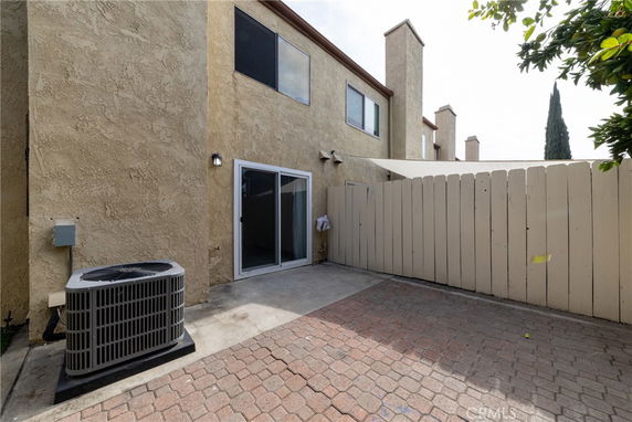 Front view of a house with sliding glass doors and an air conditioning unit.