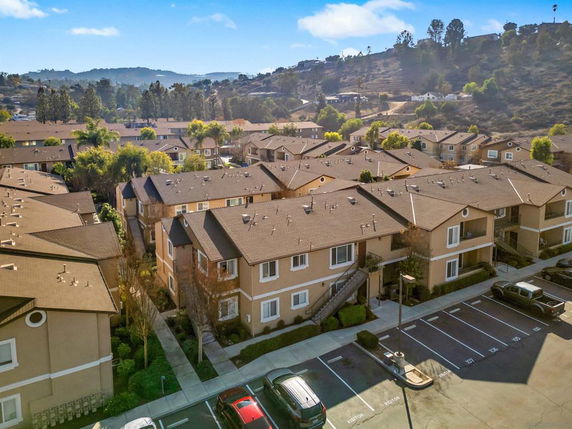 Aerial view of an apartment complex with multiple buildings and surrounding hills.