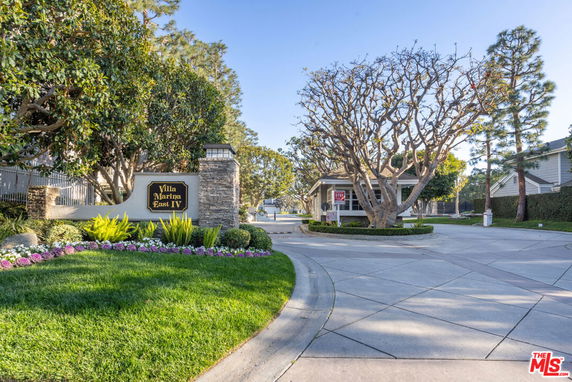 Entrance view of Villa Marina East IV with a landscaped garden and a sign.