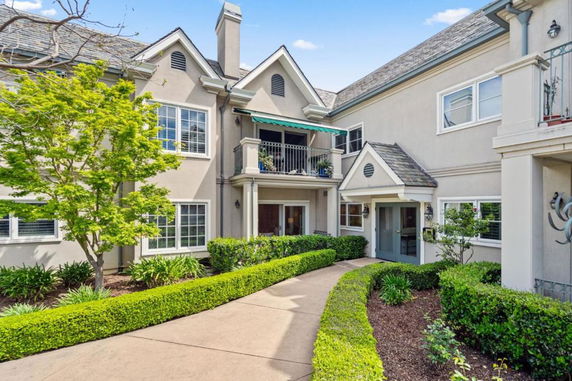Front view of a multi-story house with a balcony and well-maintained landscaping.