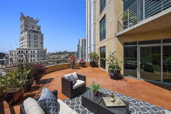 Rooftop patio with outdoor seating and view of city buildings.